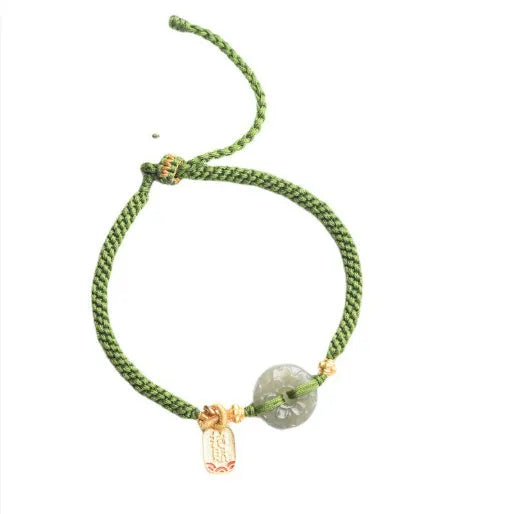 Close-up of a women's hand-woven green rope bracelet with a Hetian jade peace buckle charm.