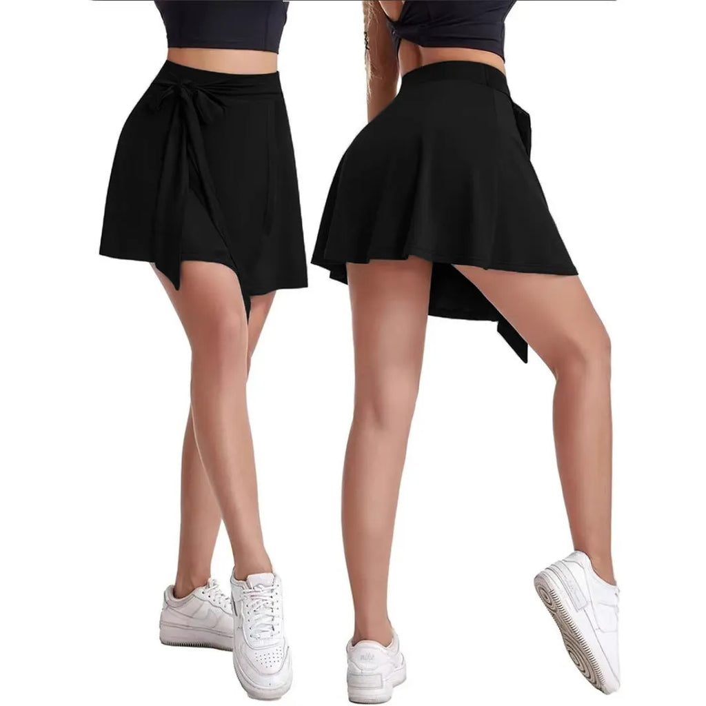 Black thigh-length sports skirt with built-in shorts, high waist, and adjustable shoulder strap on a hanger.
