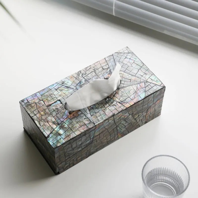 A black square shell storage box with a removable organiser insert on a coffee table.