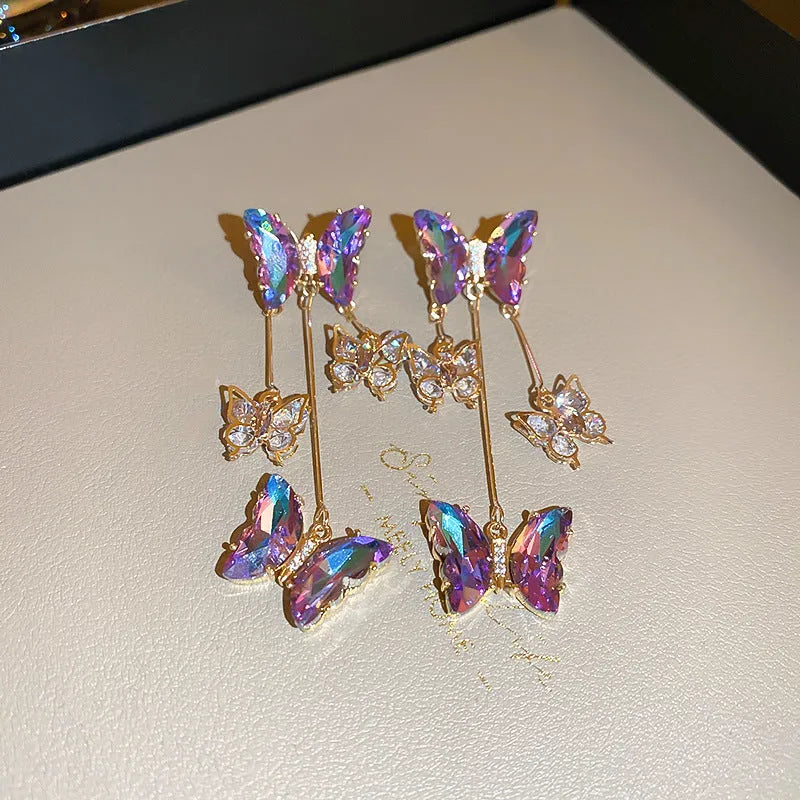 Blue purple butterfly-shaped drop earrings with crystal flowers and a metal tassel.
