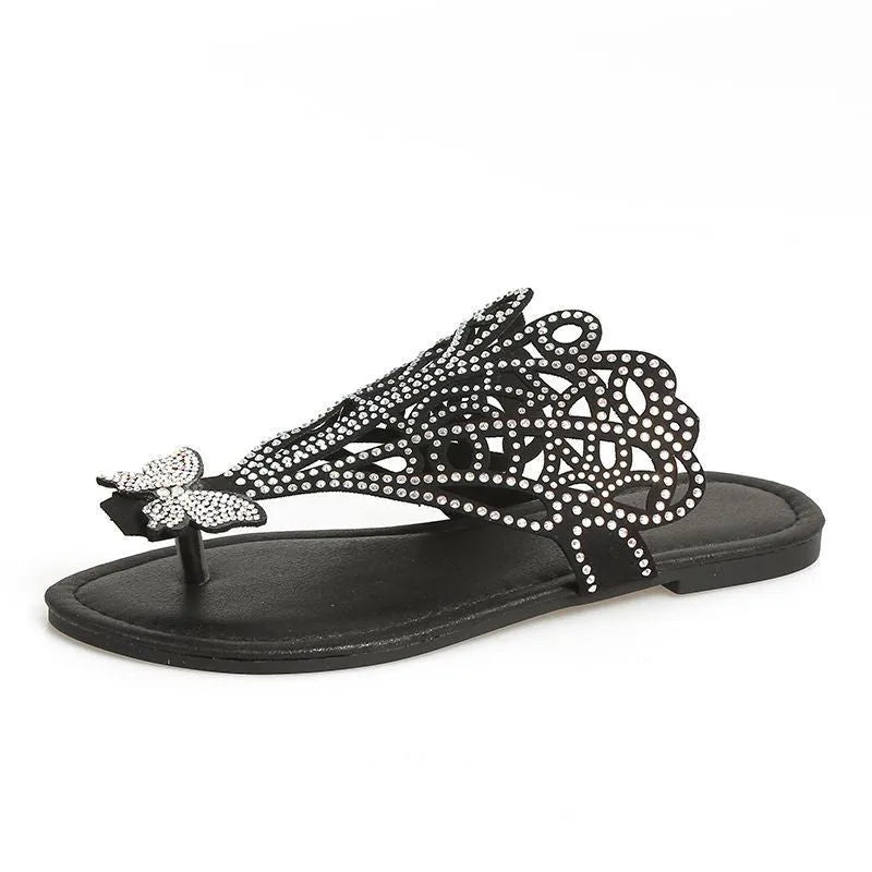 Women's black slip-on sandals with rhinestone detail, flip-toe design, and flat rubber sole.