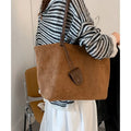 Brown suede shoulder bag with double straps and sewing line detail on a white background