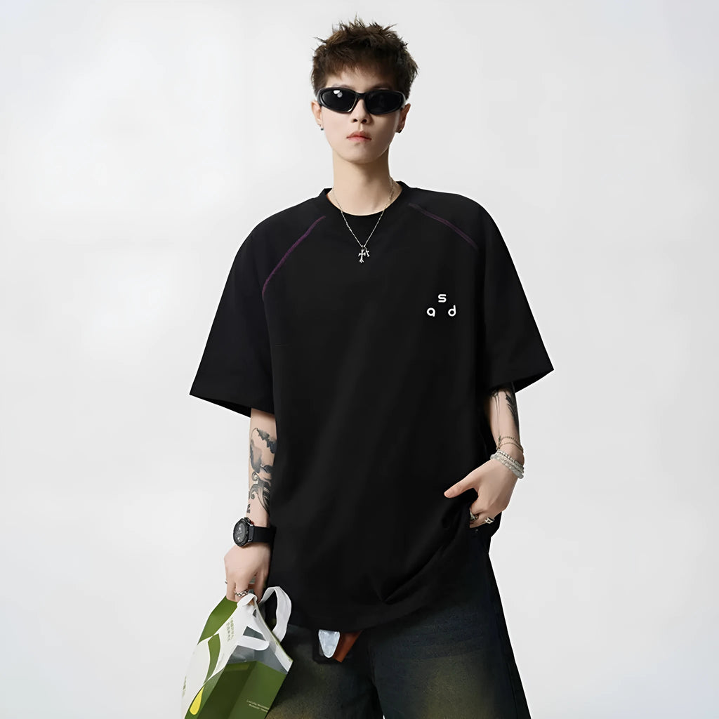 A loose-fit black cotton T-shirt with a white letter print on the front, showing a round neck and short sleeves.