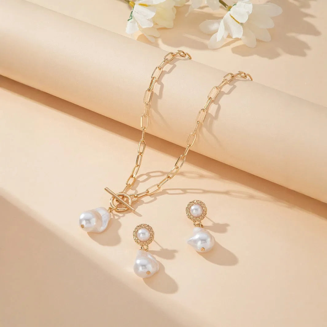 Gold-tone baroque pearl pendant necklace and matching stud earrings set on a white background.