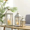 Black and white wrought iron floor storm lantern with tempered glass panels for courtyard decoration.
