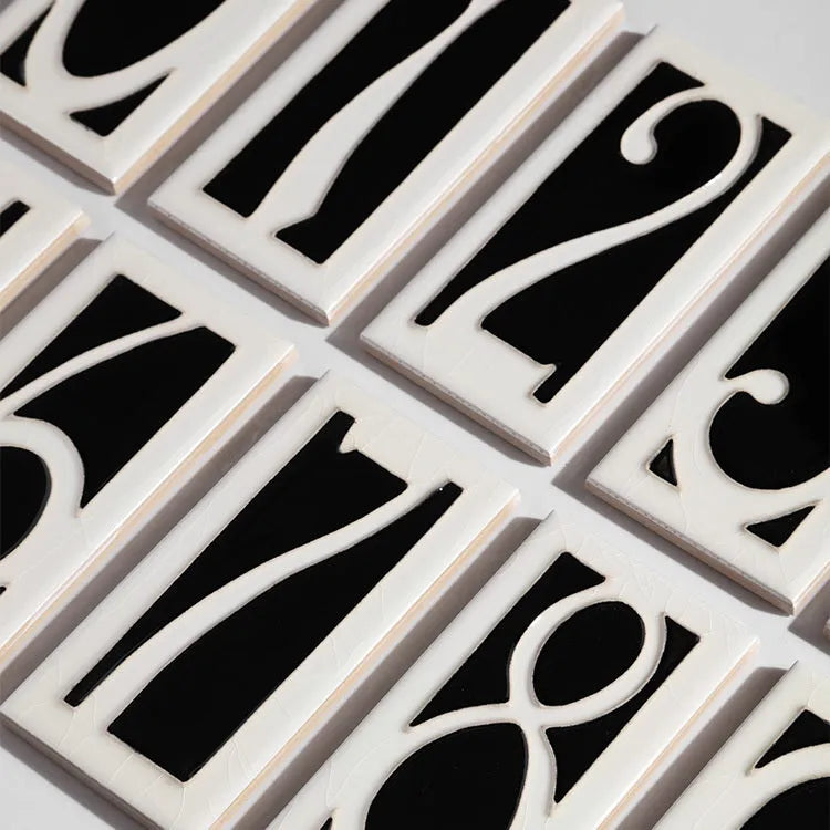 Handmade retro-style ceramic doorplate with an enamel art number on a white background.