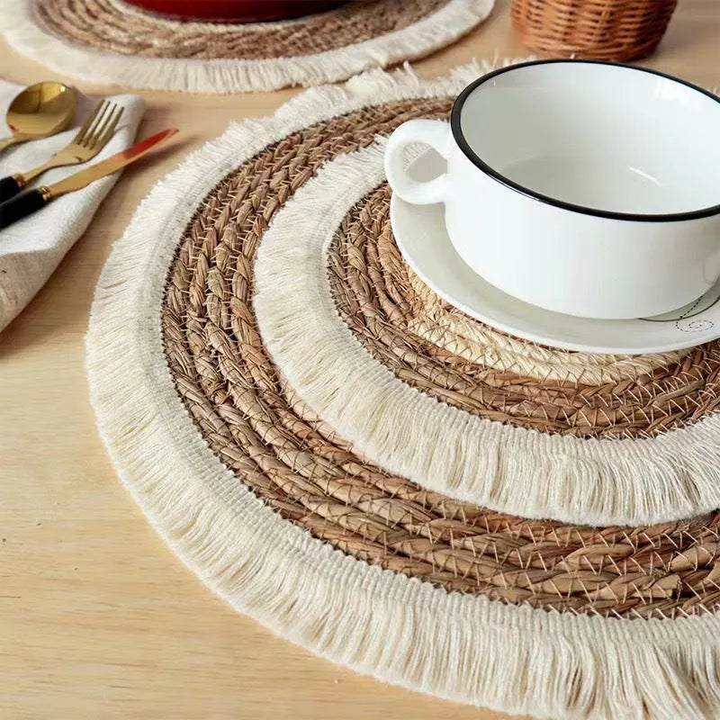 Round natural papyrus placemat on a wooden table, showing corn rope tassel detail and modern minimalist style.