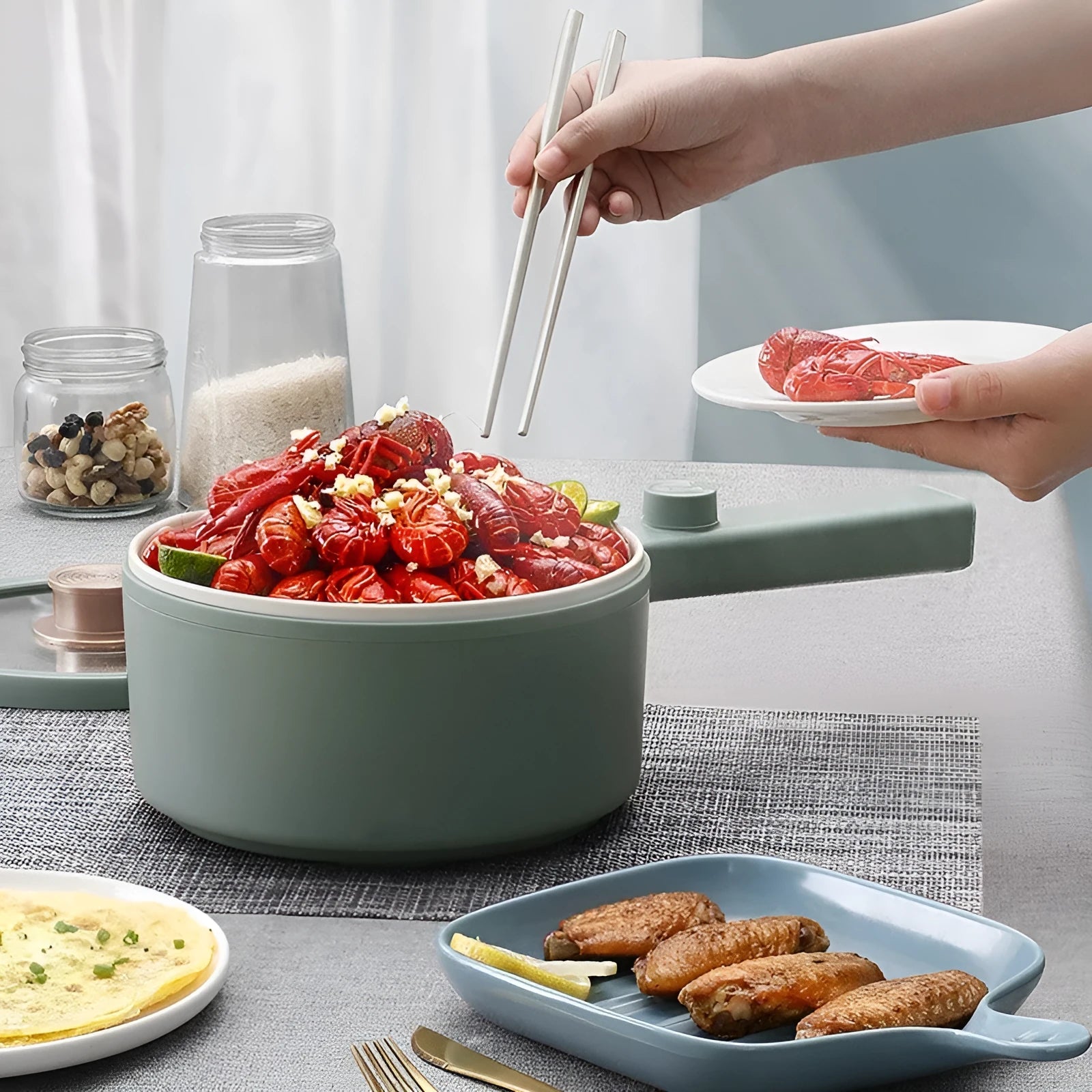 White and green multi-function electric cooking pot with temperature control dial, shown with a UK plug converter.
