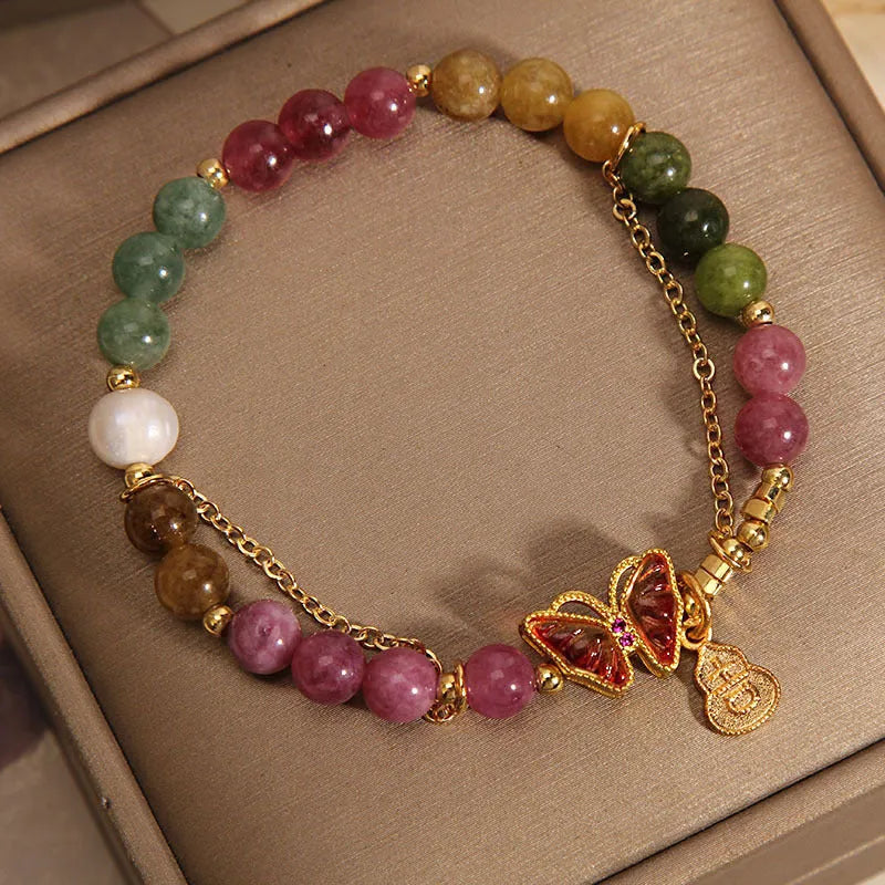 Close-up of an agate butterfly bracelet with a tourmaline-coloured gourd charm on a model's wrist.