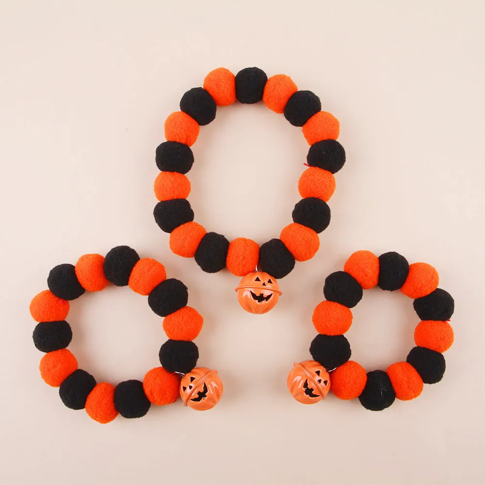 Orange Halloween cat collar with plastic pumpkin, ghost, and bat charms on a black strap.