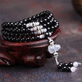 Black agate bracelet with 108 geometric beads and number details on a wrist.