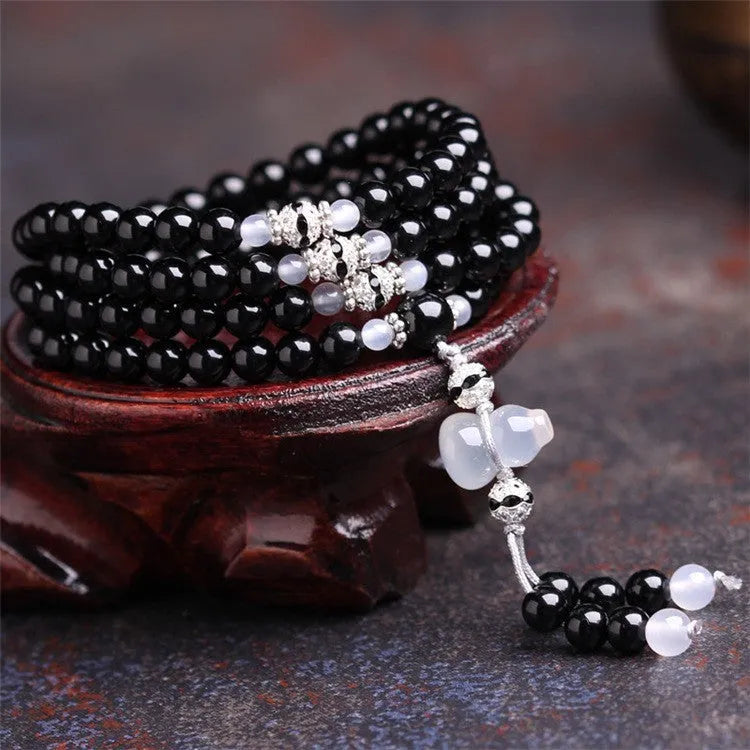 Black agate bracelet with 108 geometric beads and number details on a wrist.