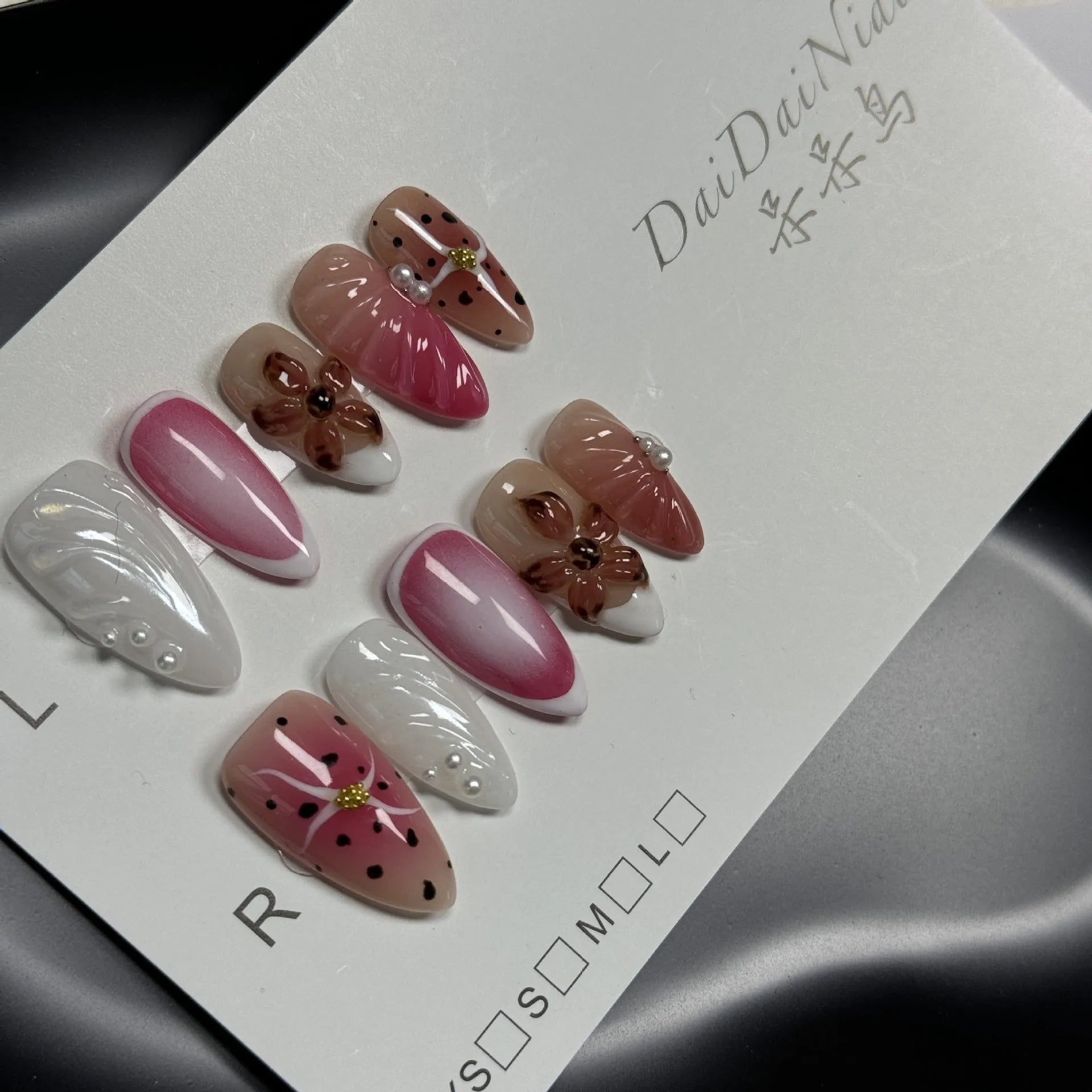 Set of hand-painted 3D carved nail beauty patches in embossed and candy patterns on a plastic sheet.