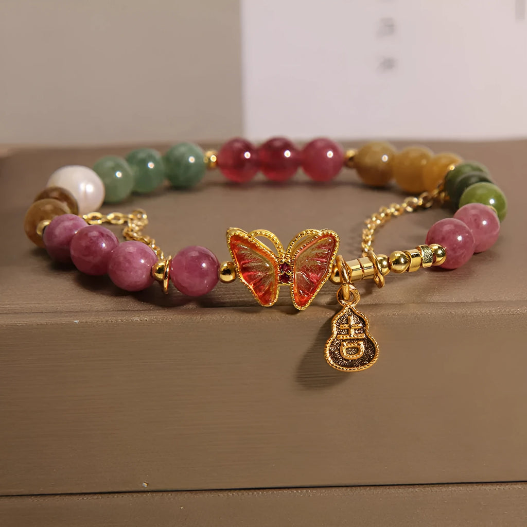 Close-up of an agate butterfly bracelet with a tourmaline-coloured gourd charm on a model's wrist.
