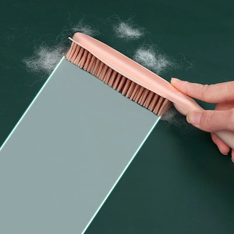 Pink and green handheld pet hair remover brush with grooming comb and integrated clothes hair collector.