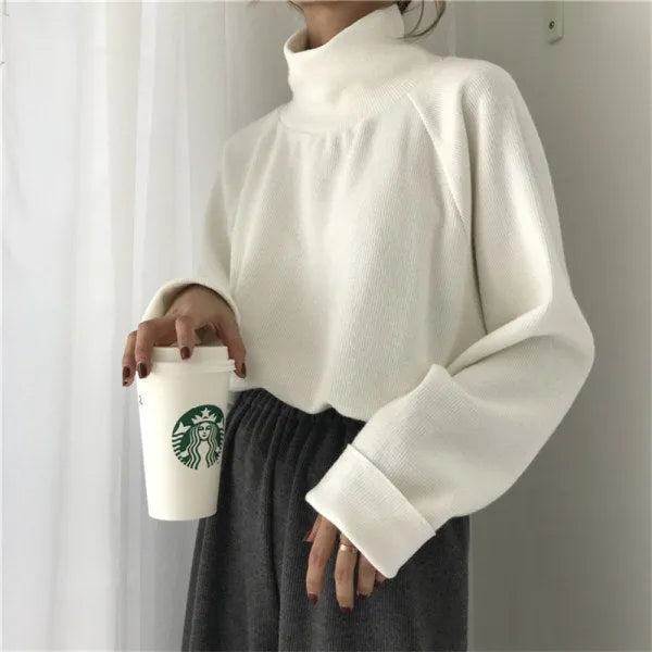 Women's loose half-high collar long sleeve top in solid apricot colour on a hanger.