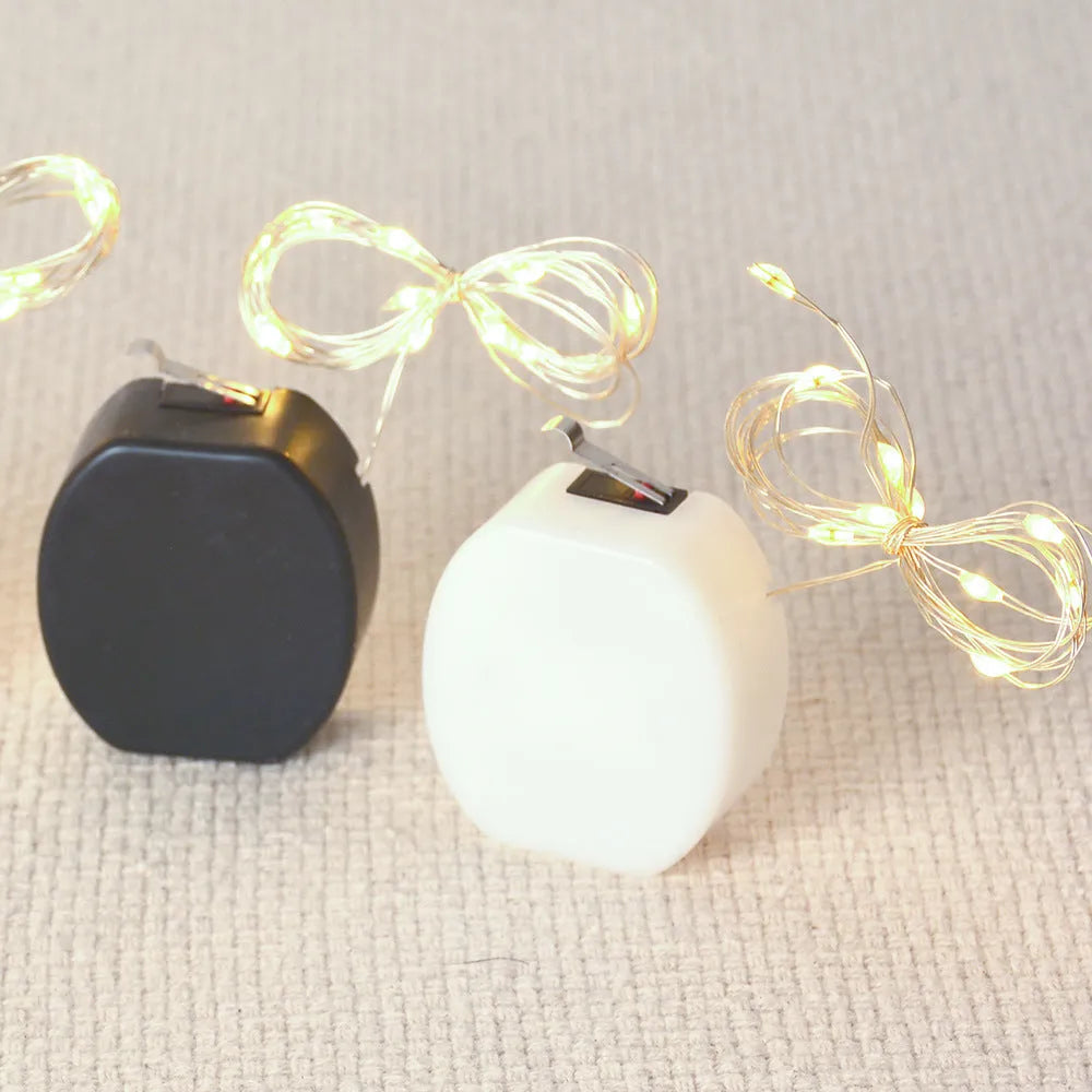 Bendable copper wire LED light string with plastic battery box, showing warm white and white light colour options.