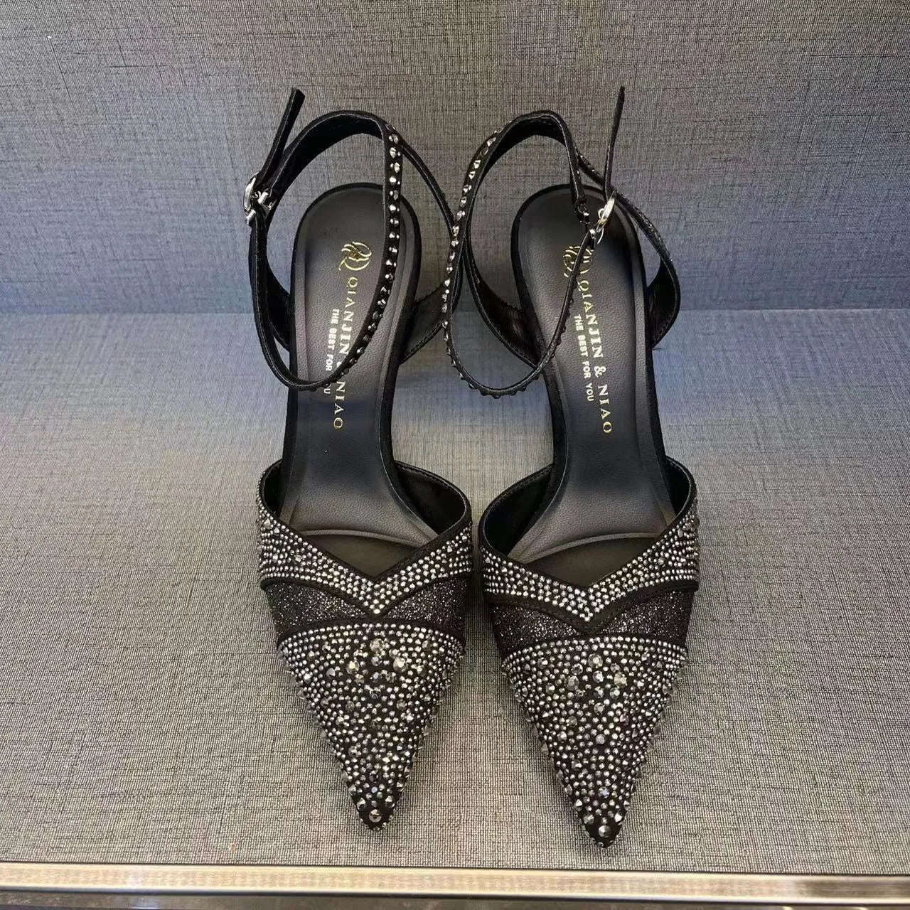 Women's black high-heeled shoes with a red sole, showing stiletto heel and pointed toe design.