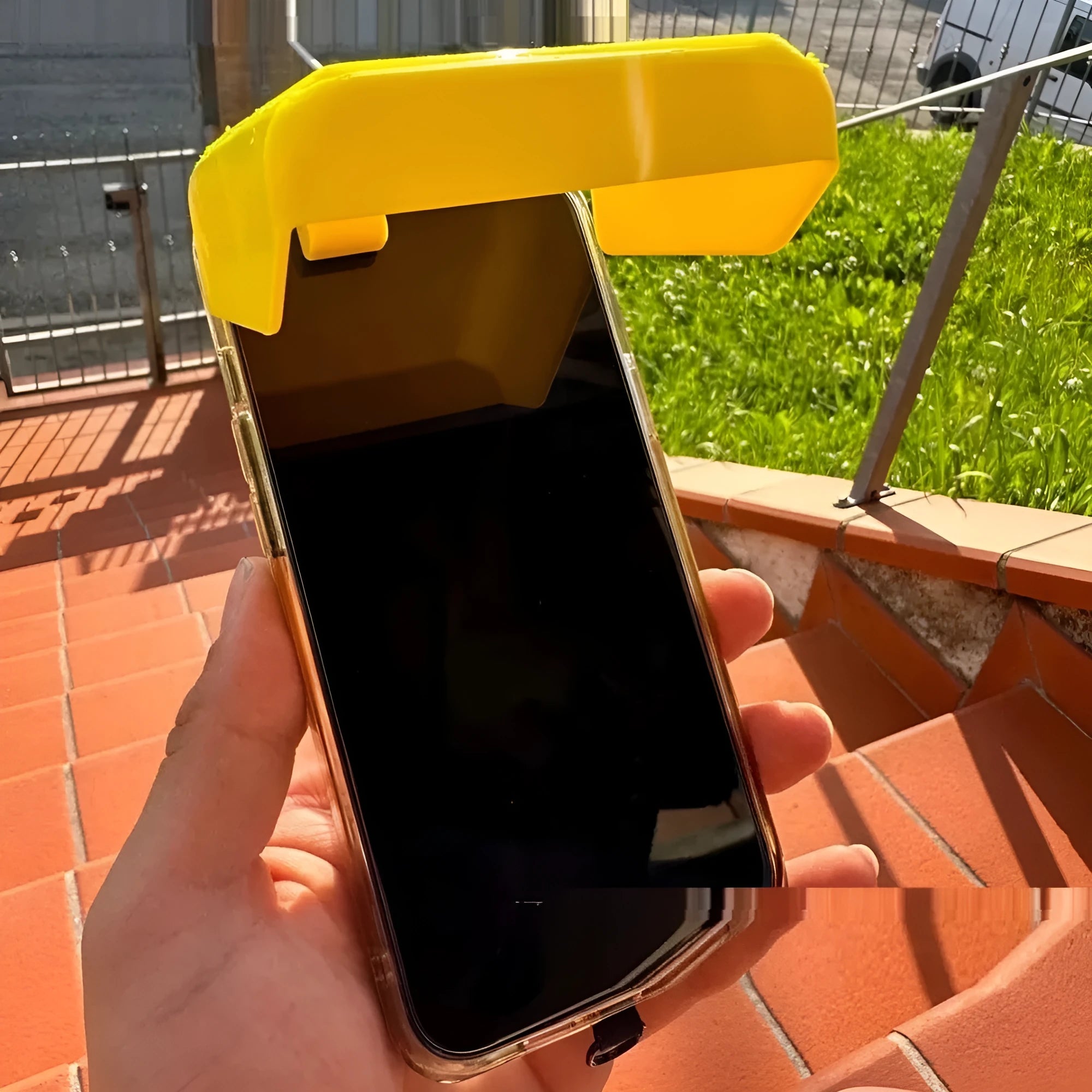 Yellow and black plastic phone clip with an attached sunshade for outdoor screen visibility.