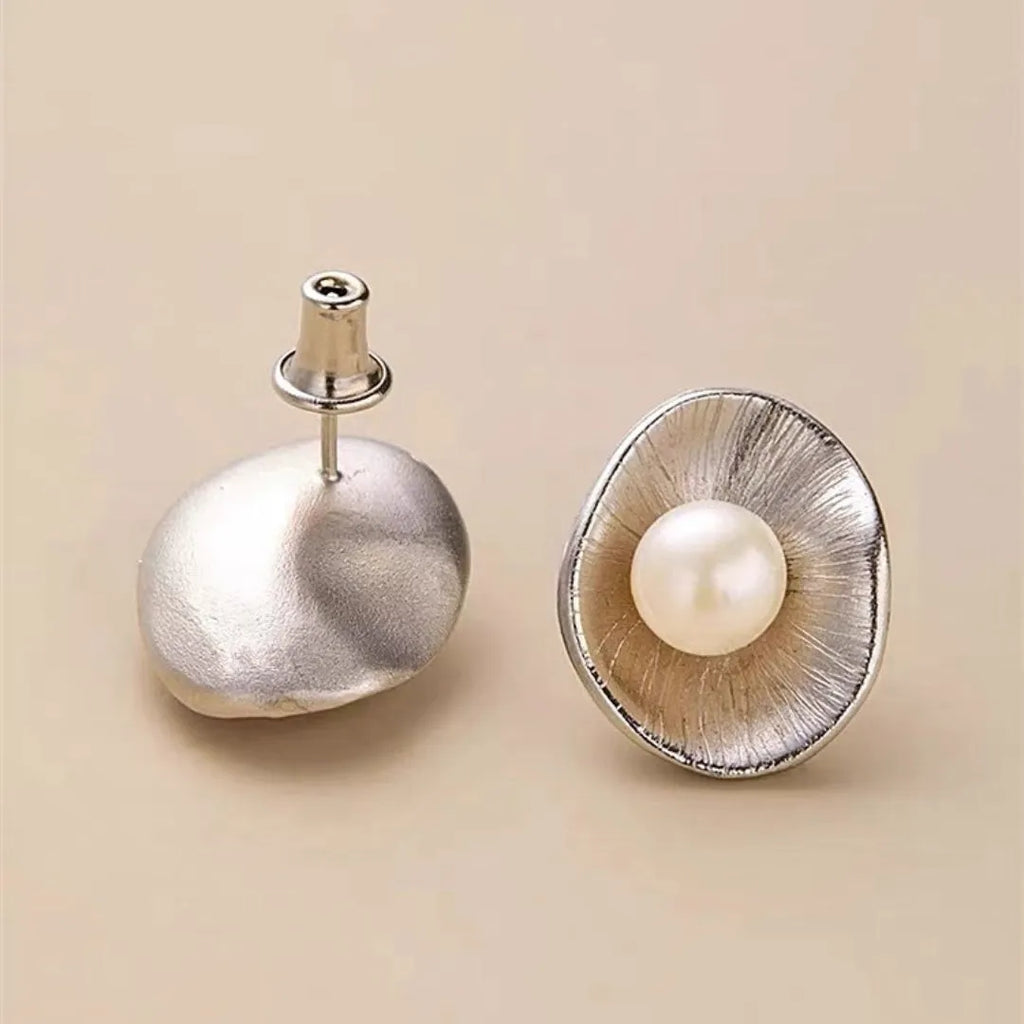 A pair of geometric sterling silver ear studs with pearl accents and a gold electroplated finish.