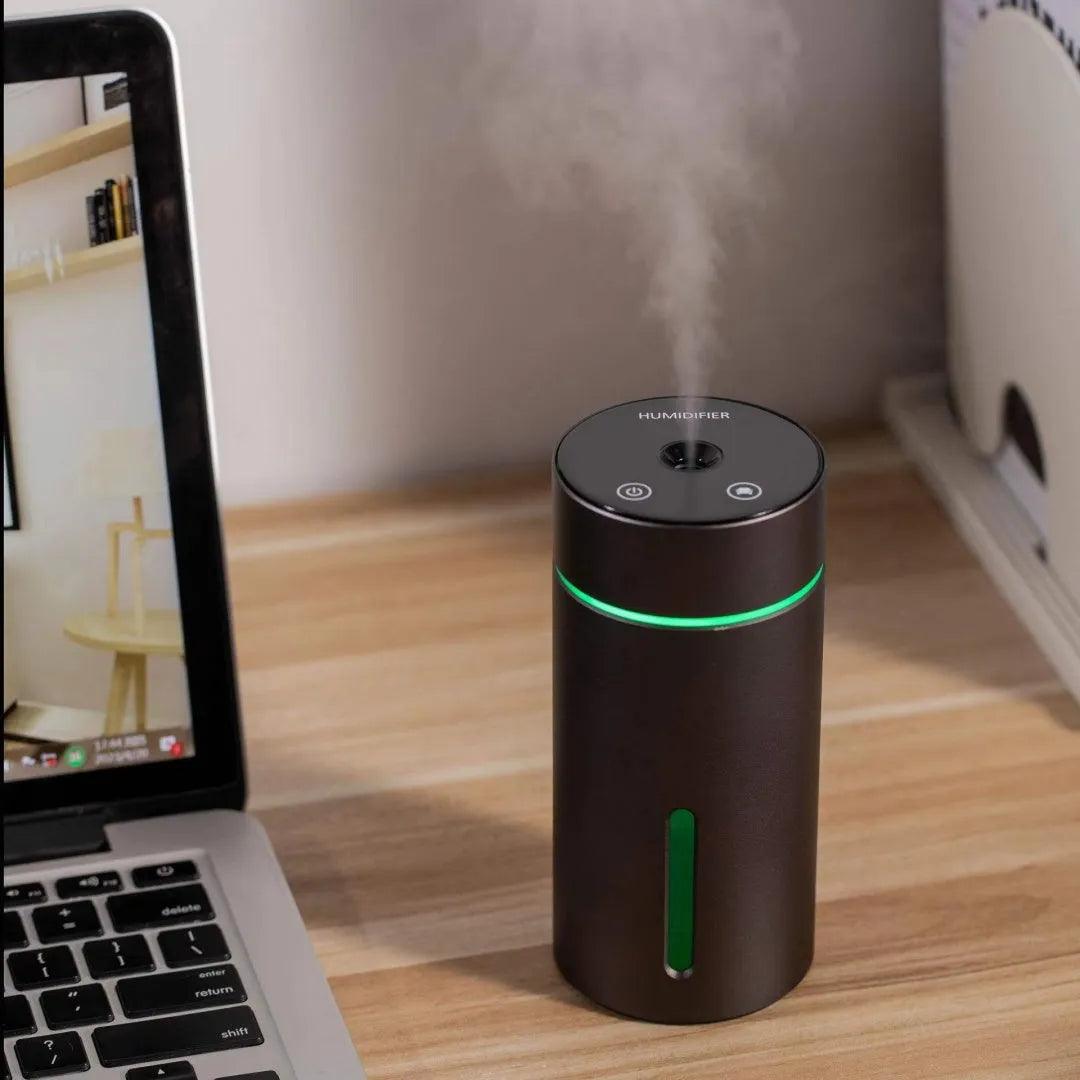 Compact aluminium car humidifier diffuser with colourful light and USB cable on a desk.