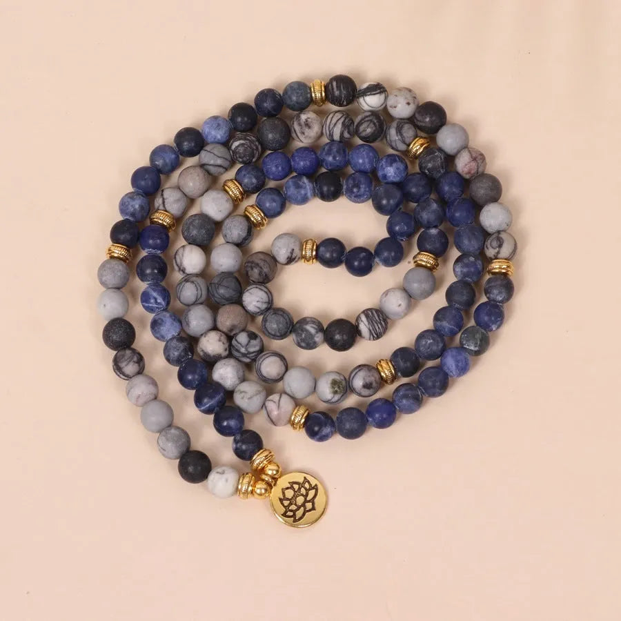 Close-up of a blue patterned network stone bead multi-layer alloy bracelet on a wrist.