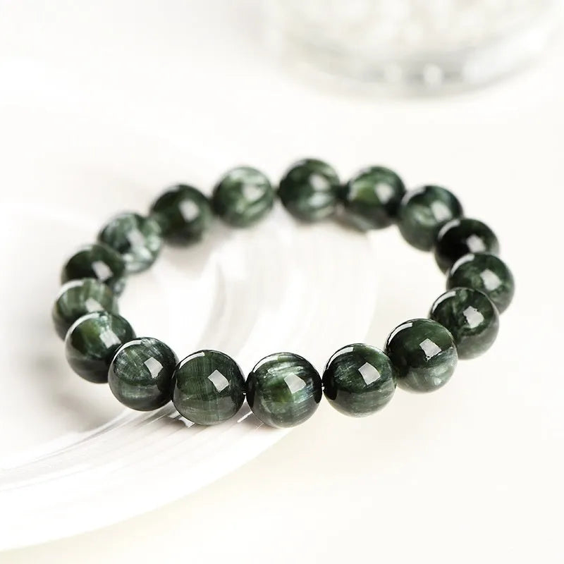 Natural green dragon crystal round bead bracelet with ruyi detail on a white background.