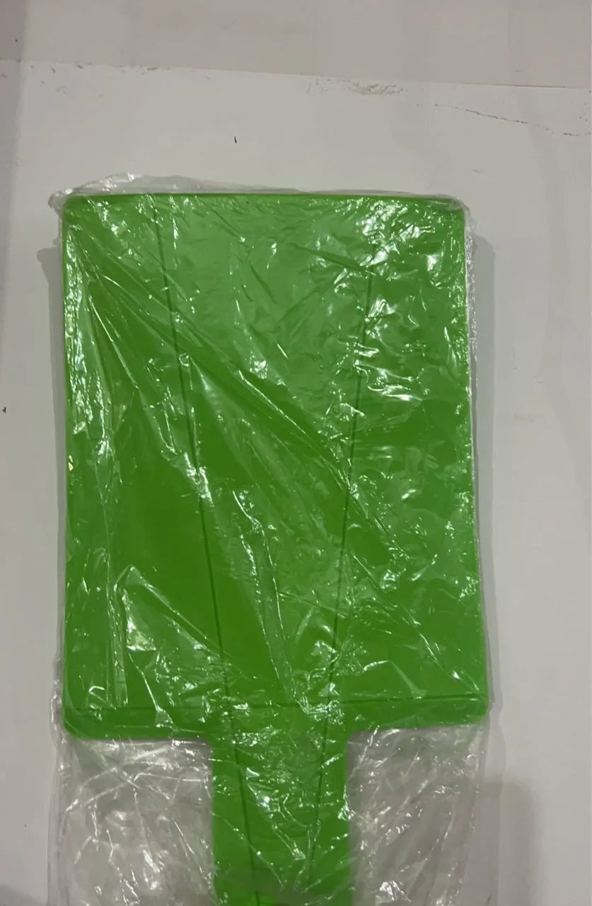 Green folding plastic cutting board with non-slip texture and hanging hole on kitchen countertop