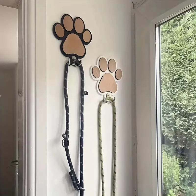 Black wooden wall hook with raised paw print design against a white wall.