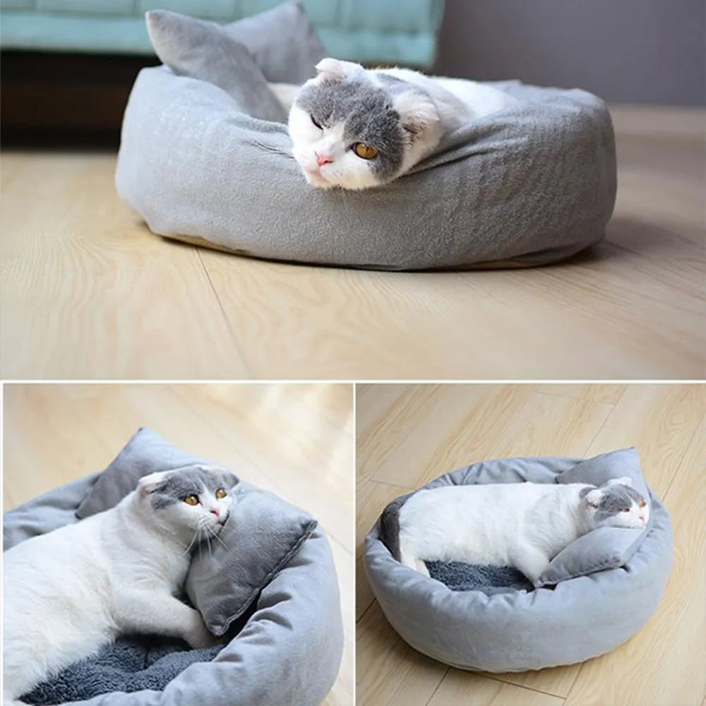 Grey round plush pet bed with pillow for small dogs and cats on a wood floor.