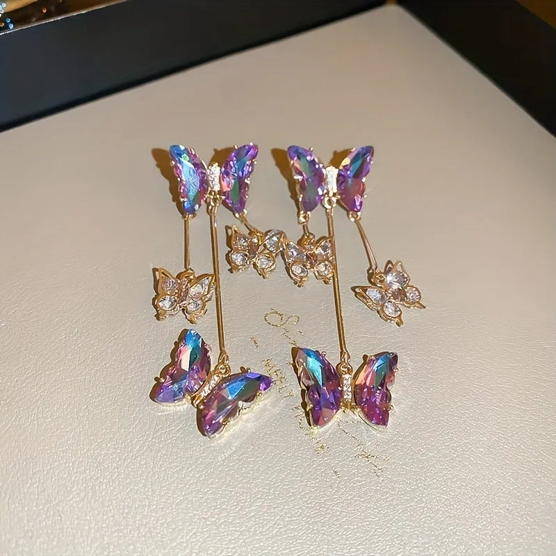 Blue purple butterfly-shaped drop earrings with crystal flowers and a metal tassel.
