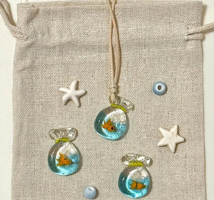 Women's necklace with coloured glaze joker pendant on a beige cotton linen clavicle chain.