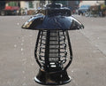 White outdoor solar mosquito lamp with solar panel on top and LED light beads, shown in a garden setting.