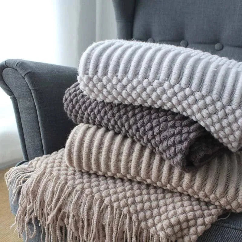 Small grey polyester nap blanket folded on a sofa, showing its size and texture.