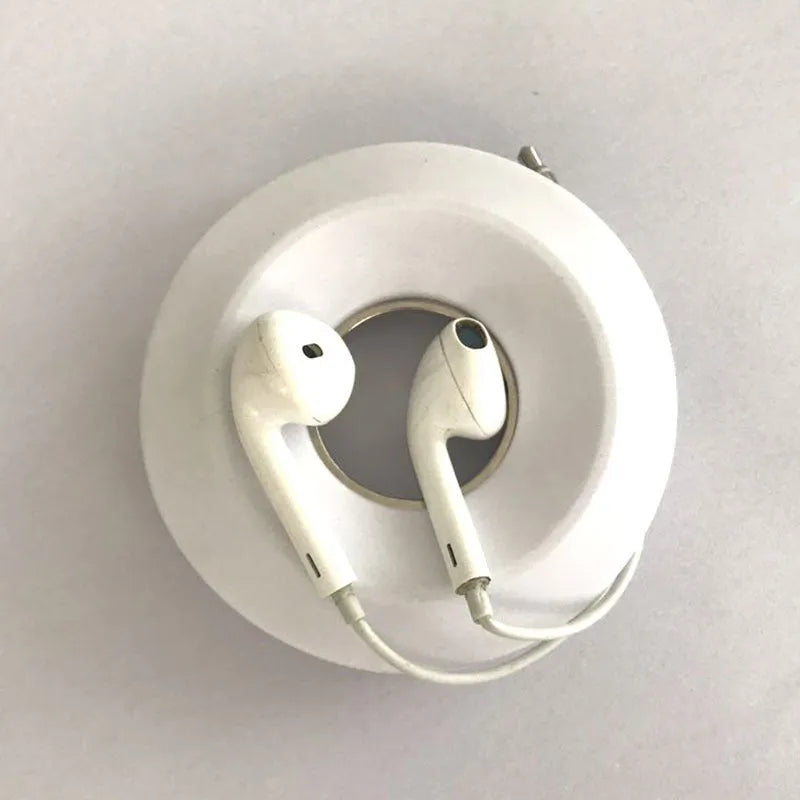 Donut-shaped silicone cord reel in three colours for organising headphones and phone cables