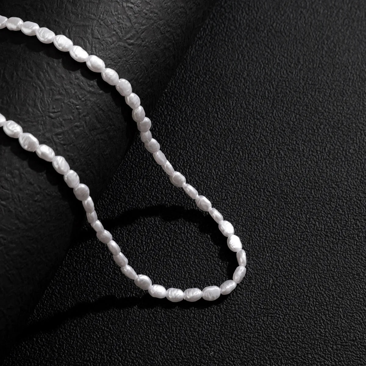 White U-shaped men's imitation pearl necklace with shellfish pendant on clavicle