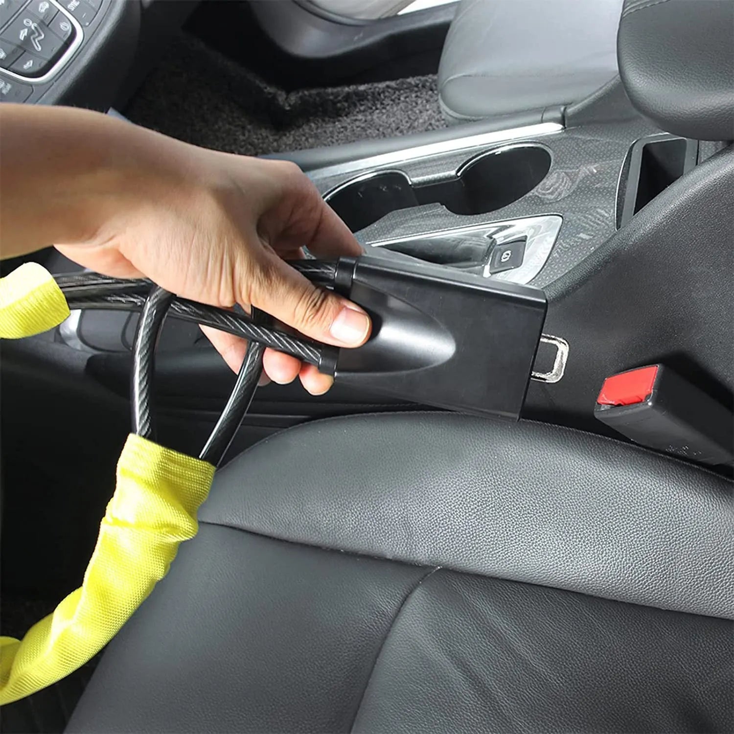 Red car steering wheel lock with iron cable secured around a steering wheel.