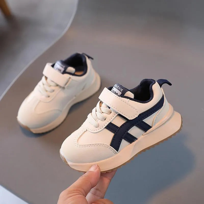 Children's solid-colour sneaker with Velcro strap, shown in beige, on a rubber sole.