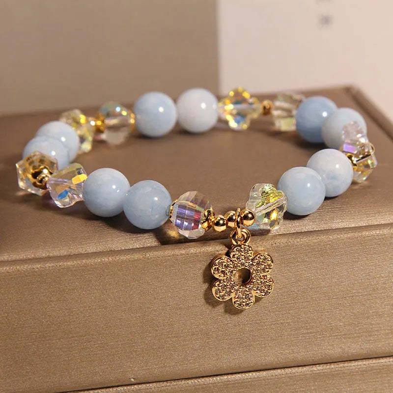 Women's aquamarine crystal bracelet with a four-leaf clover charm and pearl detail.