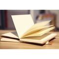 Brown kraft paper sketchbook open flat showing textured drawing pages and wireless binding.