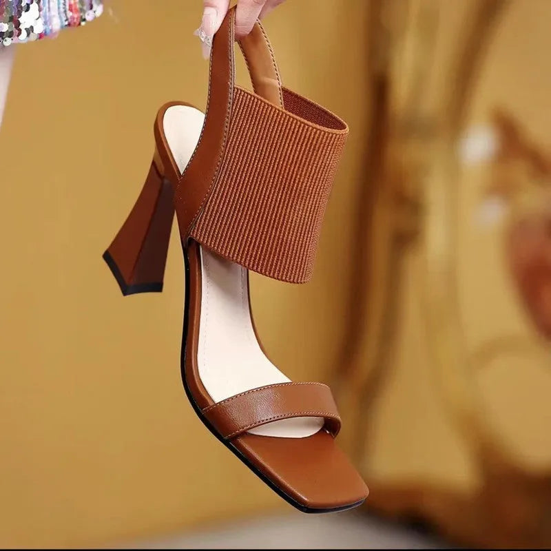 Women's high heel sandals with elastic straps in black, shown from the side.