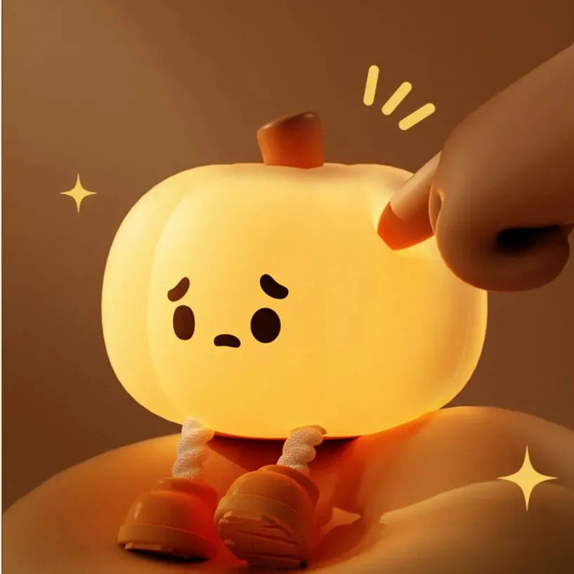 Soft orange silicone pumpkin-shaped night light with a warm glowing face on a table.