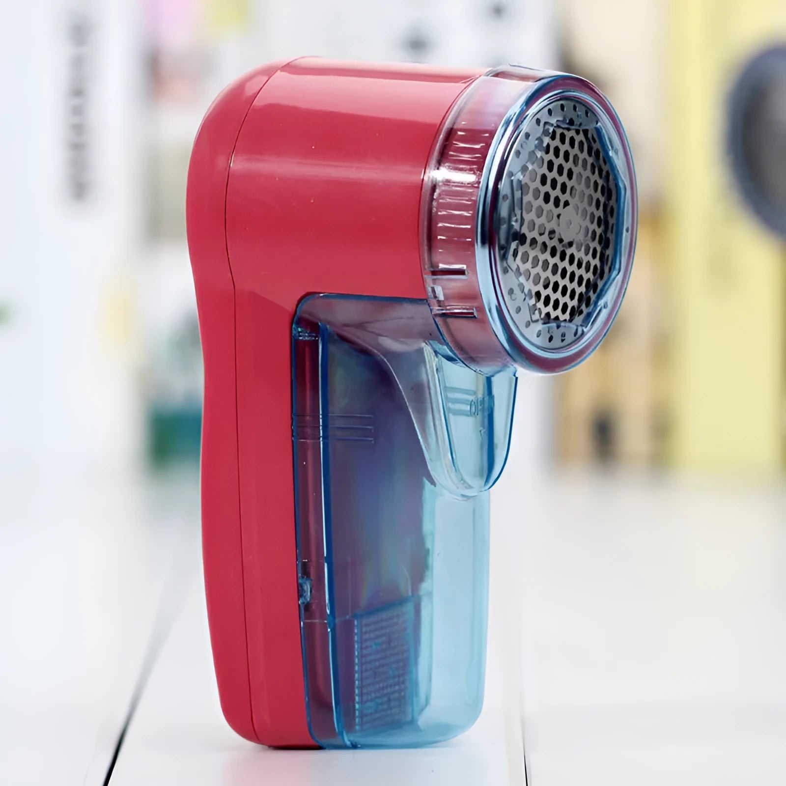 Portable electric lint remover shaver for clothing on a blue background.