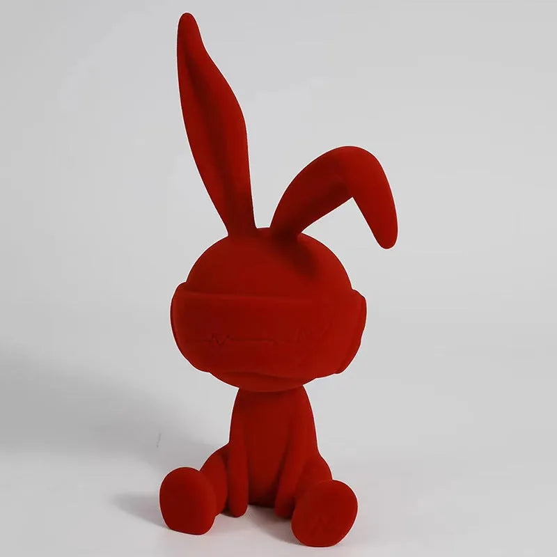 Green suede blindfold rabbit resin table ornament on a wooden surface.
