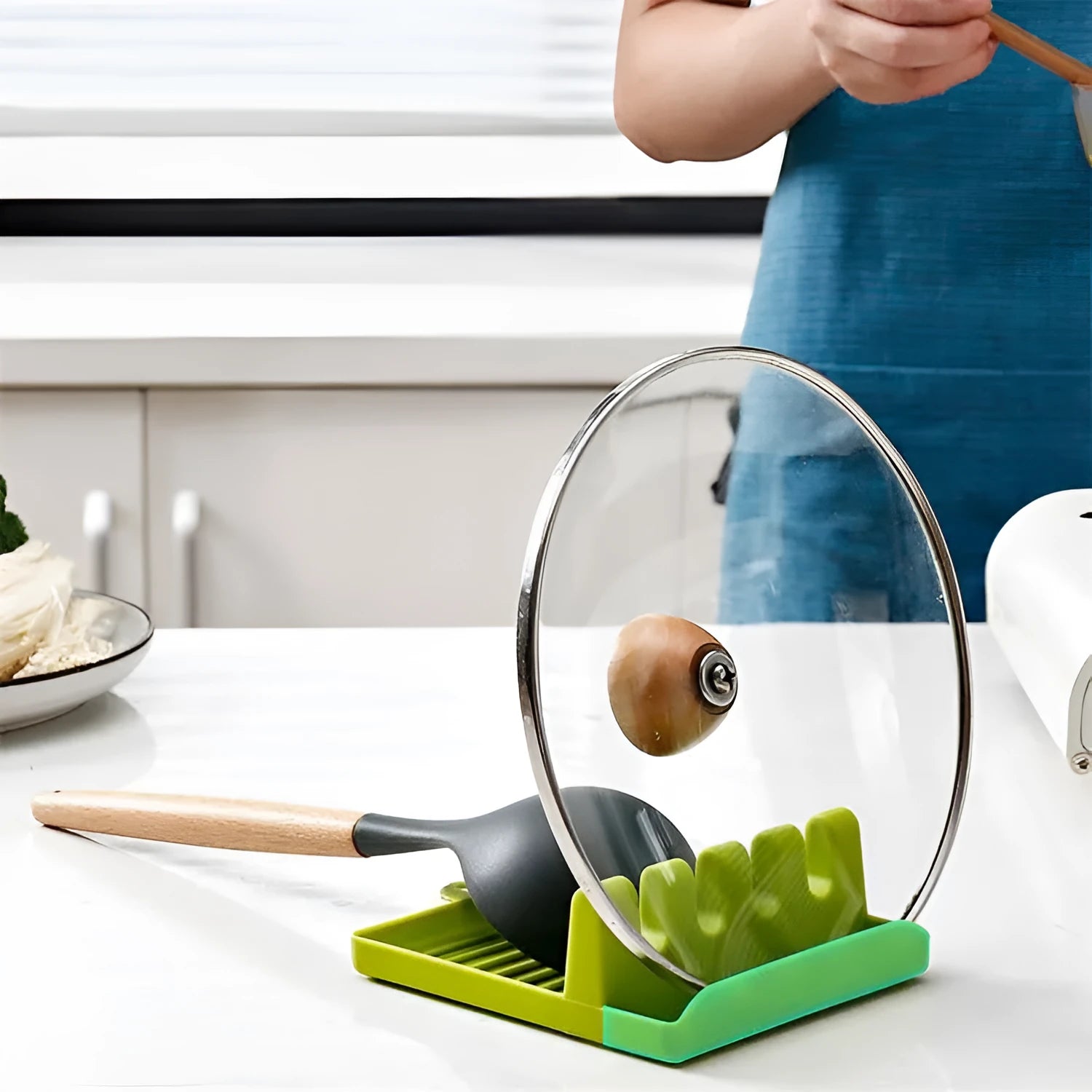 Green silicone kitchen utensil holder with four holes holding spatula, spoon, knife, and chopsticks on countertop