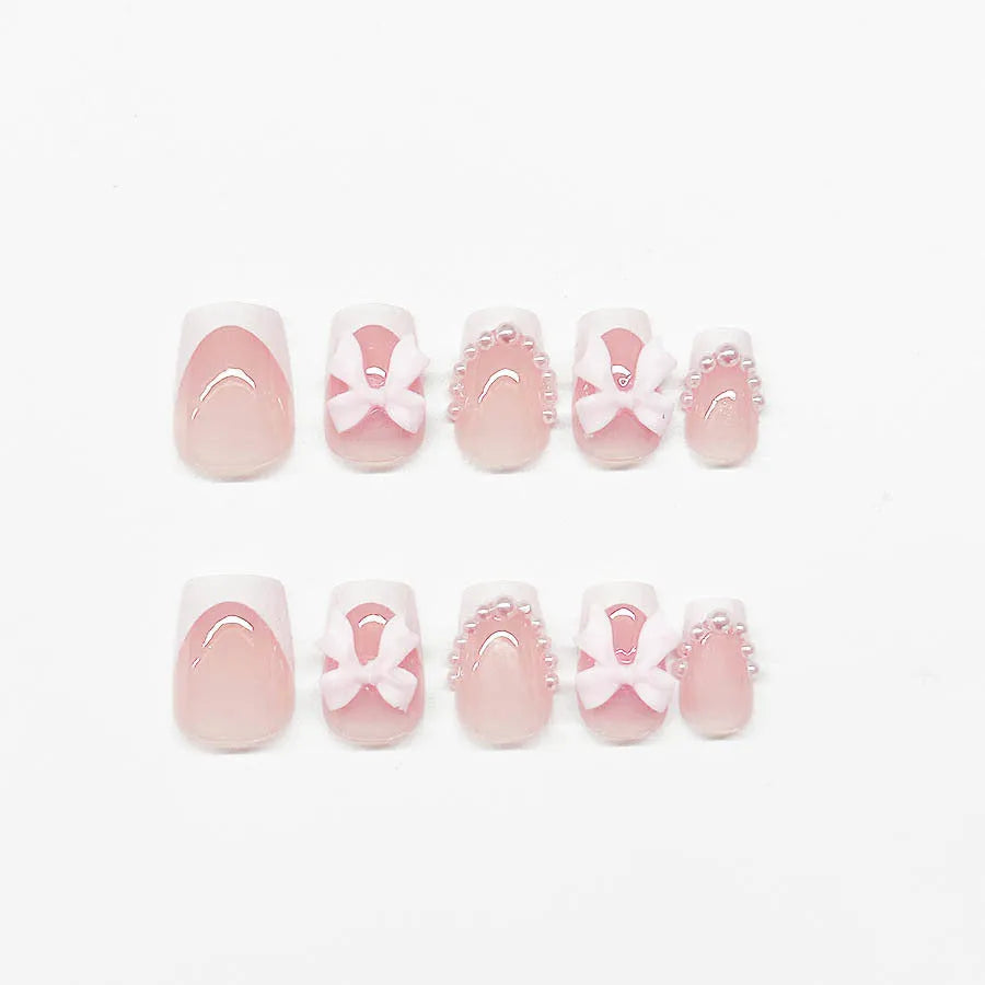 Short square French manicure artificial nails with white bow and floral patterns.