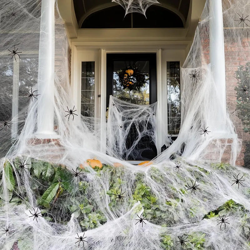 Halloween cotton spider web decoration with white plastic spiders on a dark background