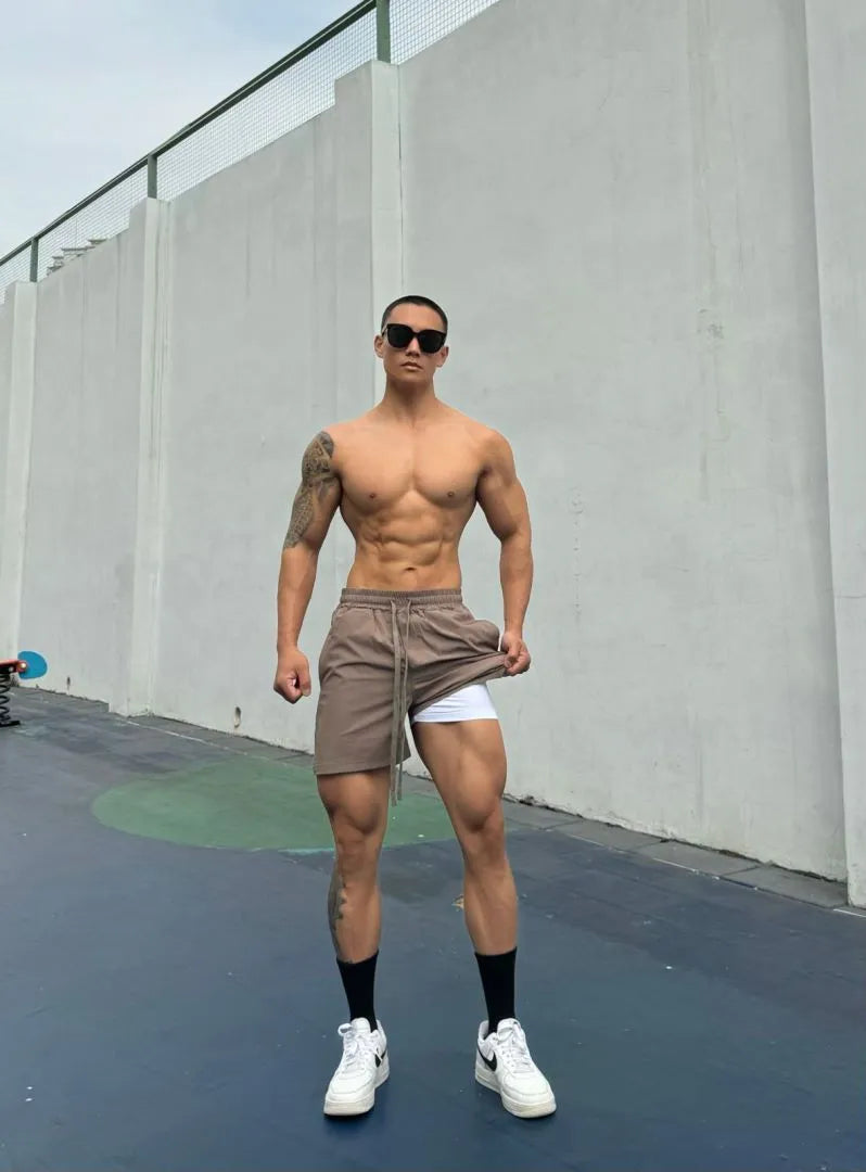 Man wearing ice silk quick-dry double-layer shorts in light grey, showing casual fit.