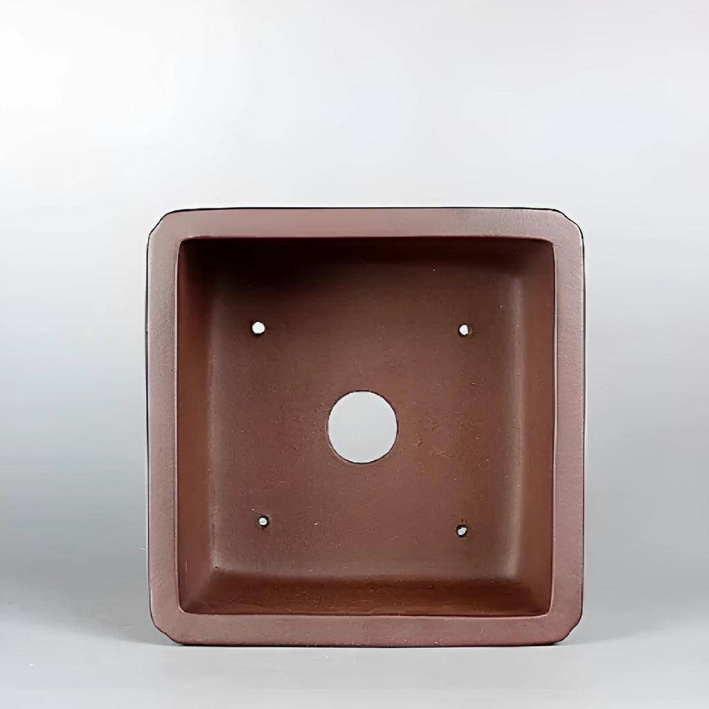 Brown handmade antique purple clay flower pot for plants on a windowsill.