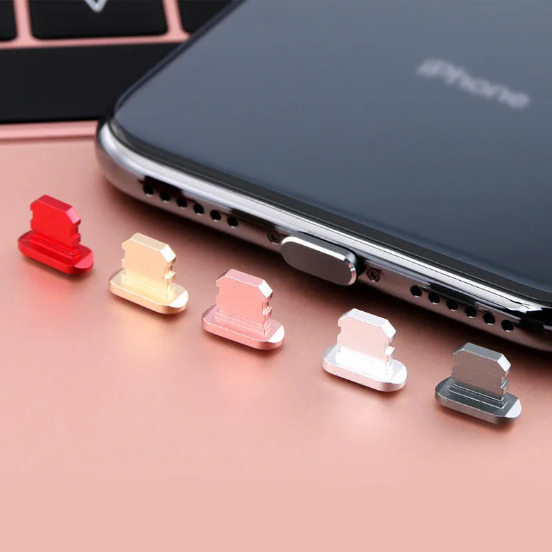Aluminum alloy iPhone charging port dust plug in rose gold colour on a grey background.